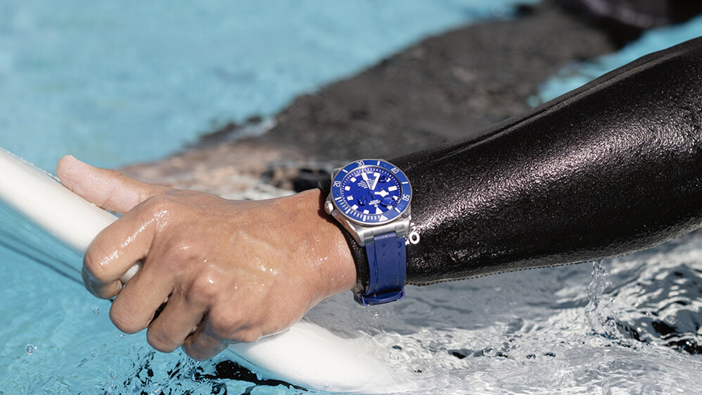 Hand auf Surfbrett mit einer TUDOR Uhr